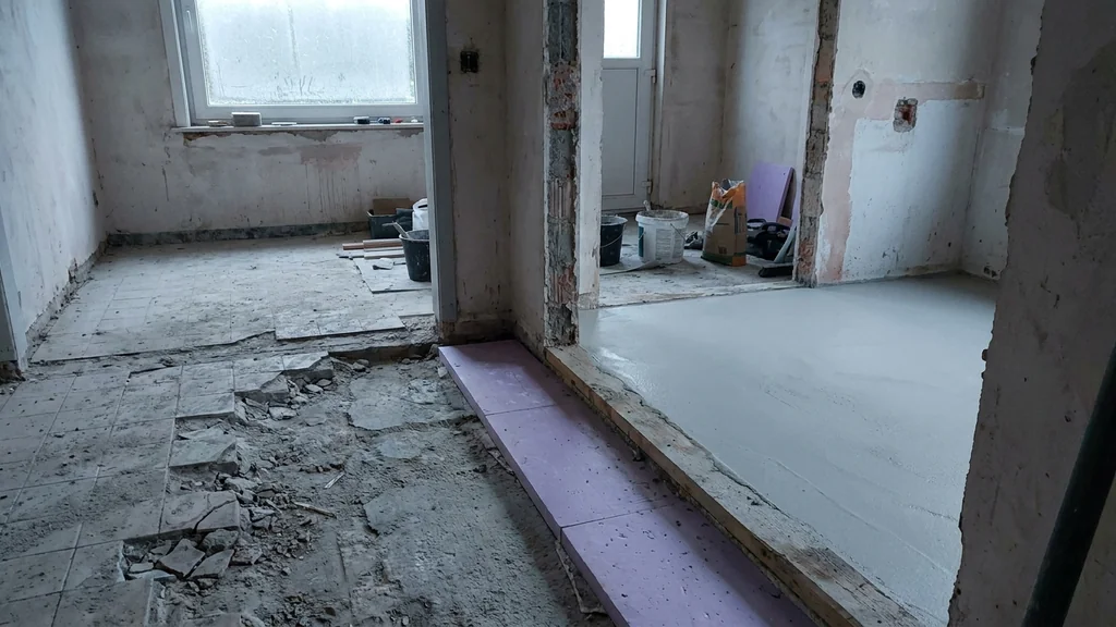 Renovatie-interieur met halve vloer opgebroken oude tegels en halve vloer met vers gelegde dunlaag-chape op PUR-isolatie - contrast tussen oud en nieuw werk